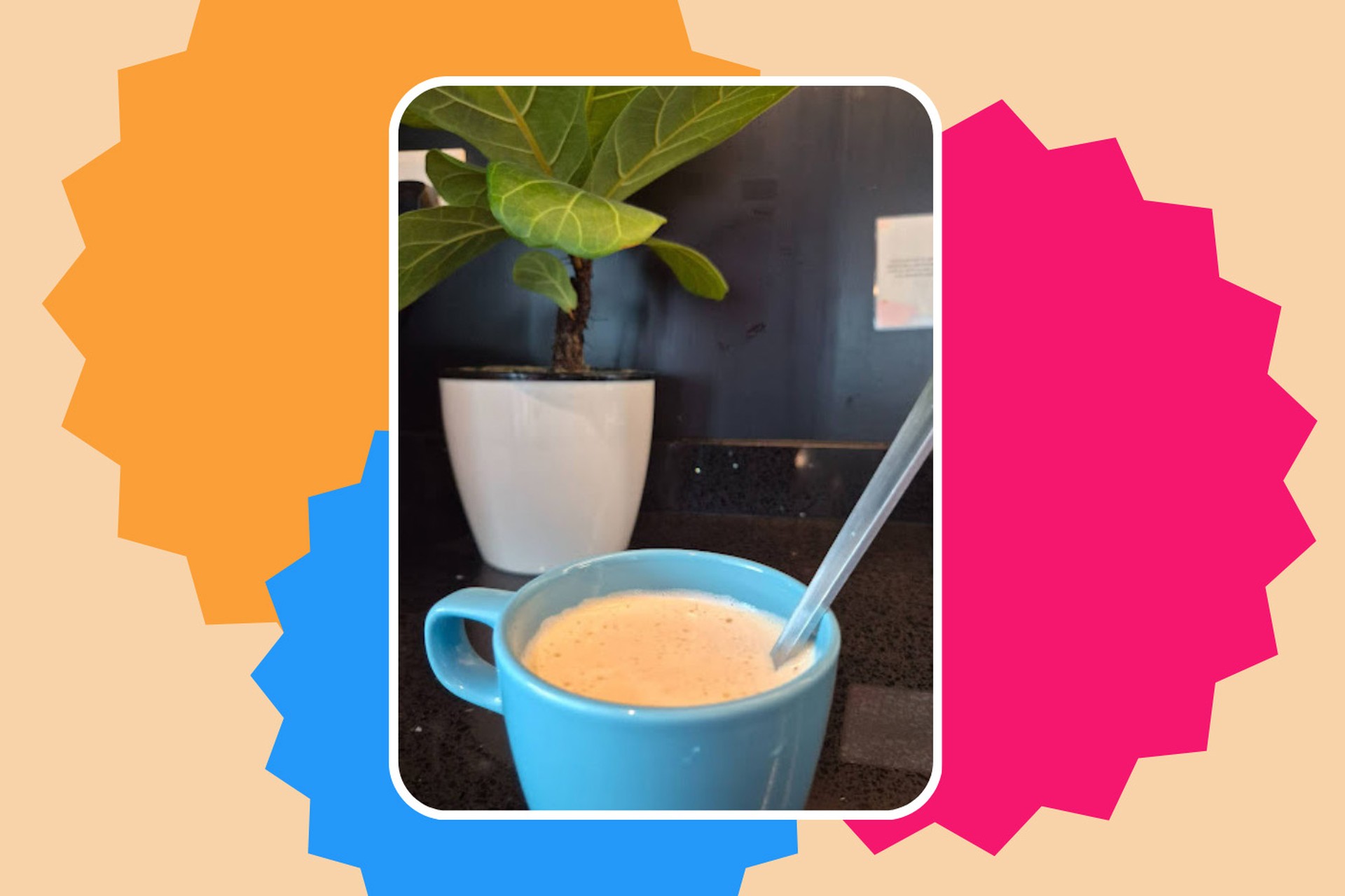 cup of coffee in a blue mug with a spoon in front of a blue wall and plant